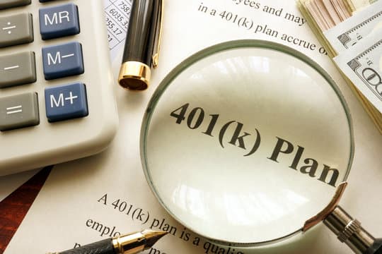 Magnifying glass over a document labeled 401(k) Plan beside a calculator and U.S. currency